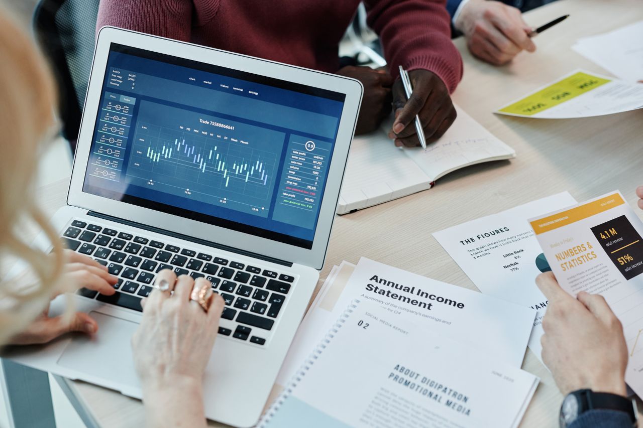 services-img Business professionals analyzing financial data on a laptop during a meeting. Charts and reports visible.